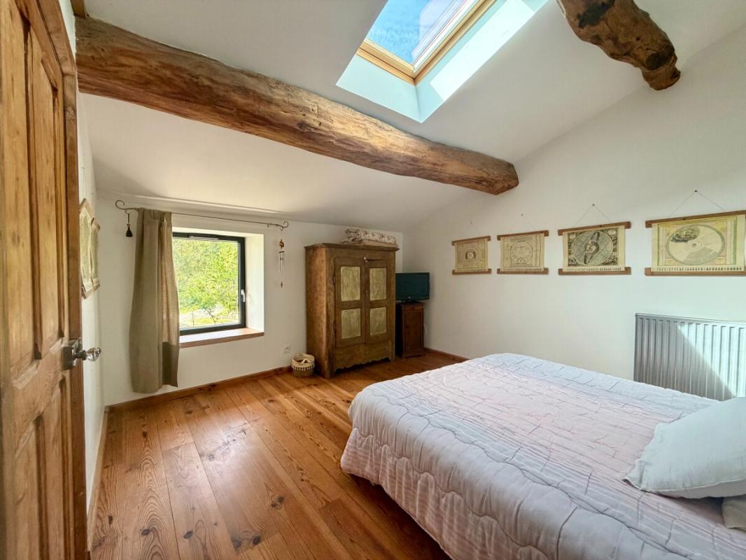 Chambre dans un corps de ferme rénové Chambre d'un corps de ferme rénové avec poutres apparentes et fenêtre sur l'extérieur.
