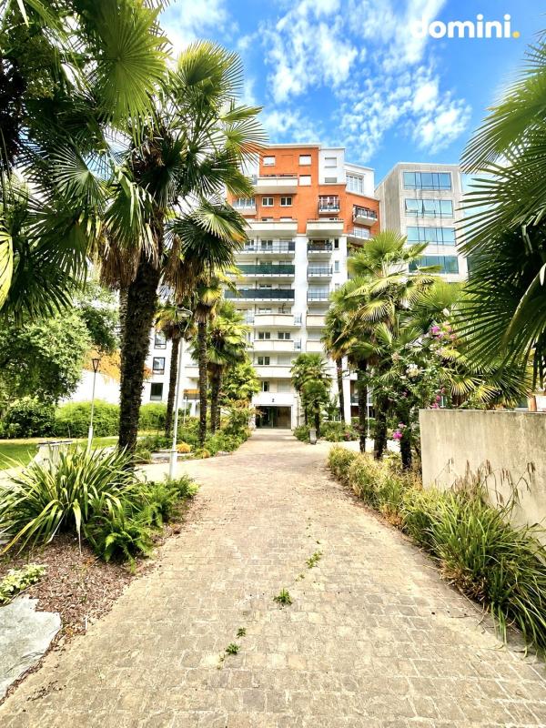 Entrée de la copropriété à Montrouge Vue de l'entrée d'une copropriété moderne avec des palmiers et un chemin en pavés à Montrouge.