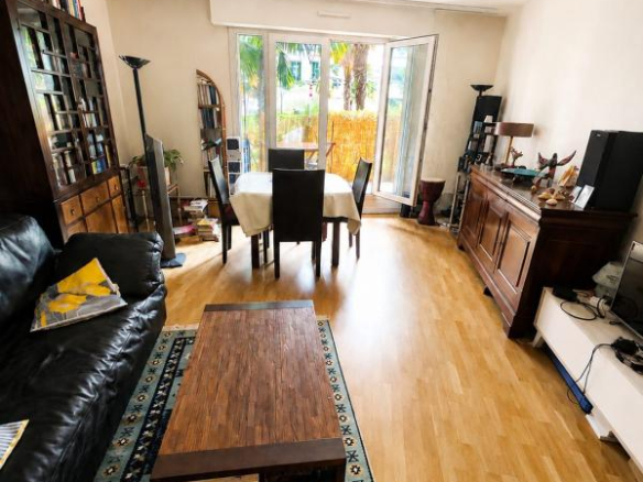 Intérieur d'un appartement à Montrouge avec un salon, une table à manger et un accès à une terrasse.