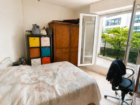 Chambre d'appartement à Montrouge avec lit, armoire et accès à une terrasse.