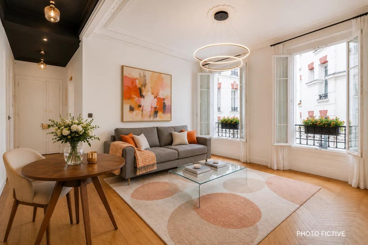 Interior of a renovated apartment with living room, dining table and windows overlooking a tree-lined courtyard.