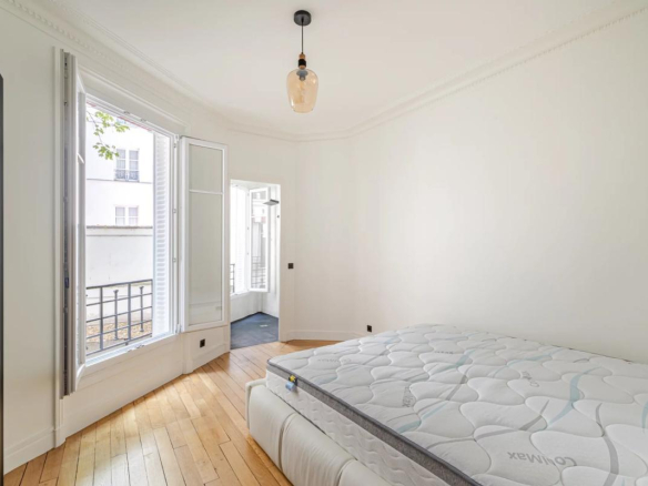 Room in a renovated 75m² apartment in Paris 7th arrondissement, with a bed and windows overlooking a tree-lined courtyard.