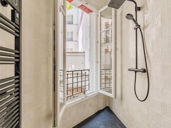 Modern bathroom with shower and window overlooking a tree-lined courtyard.
