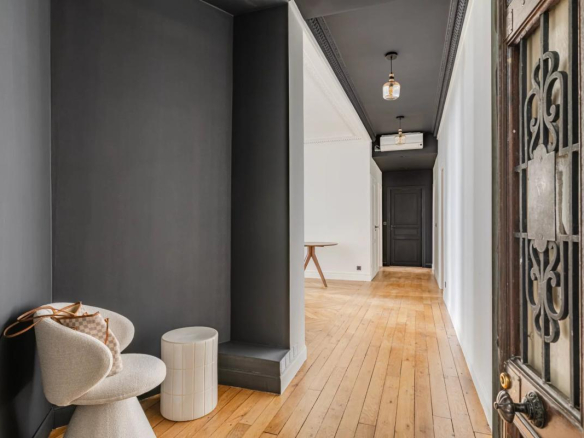 Entrance to a renovated 75m² apartment with wooden flooring and dark walls.