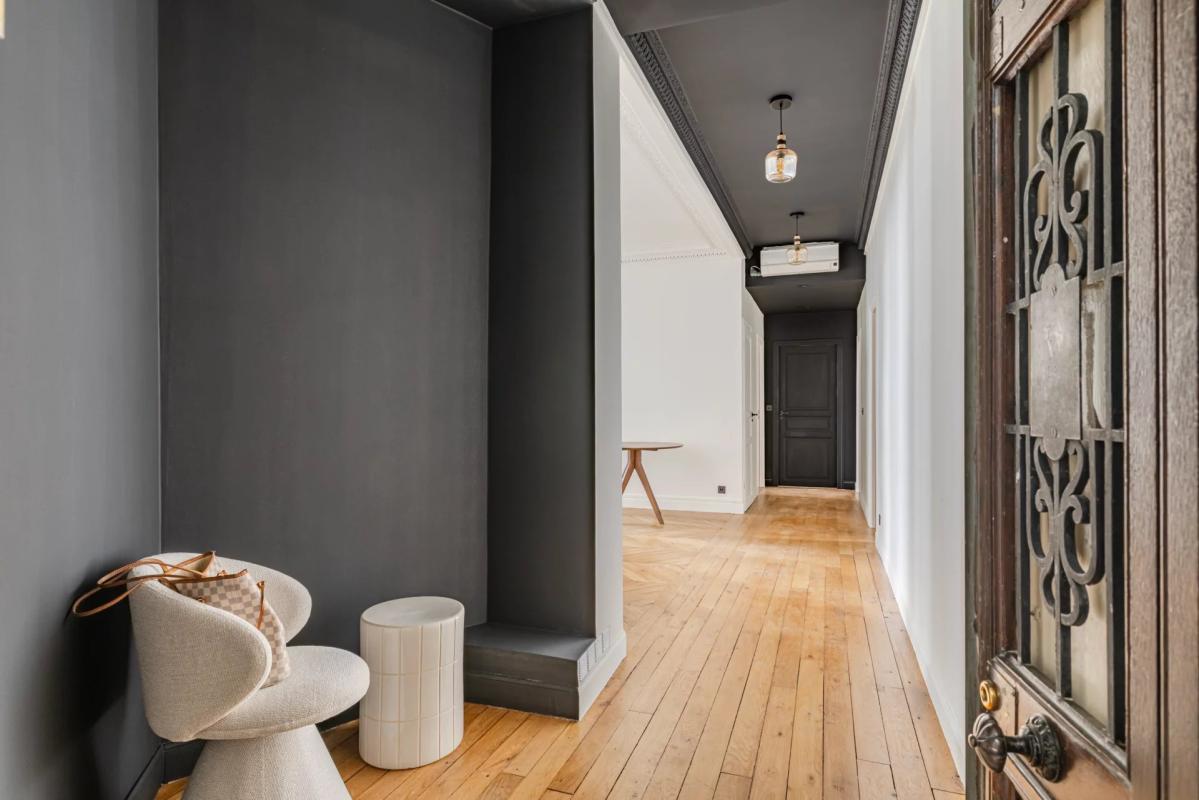 Entrance to a renovated 75m² apartment with wooden flooring and dark walls.