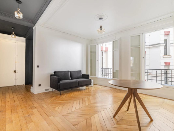 Interior of a renovated 75m² apartment with a living room and windows overlooking a tree-lined courtyard.