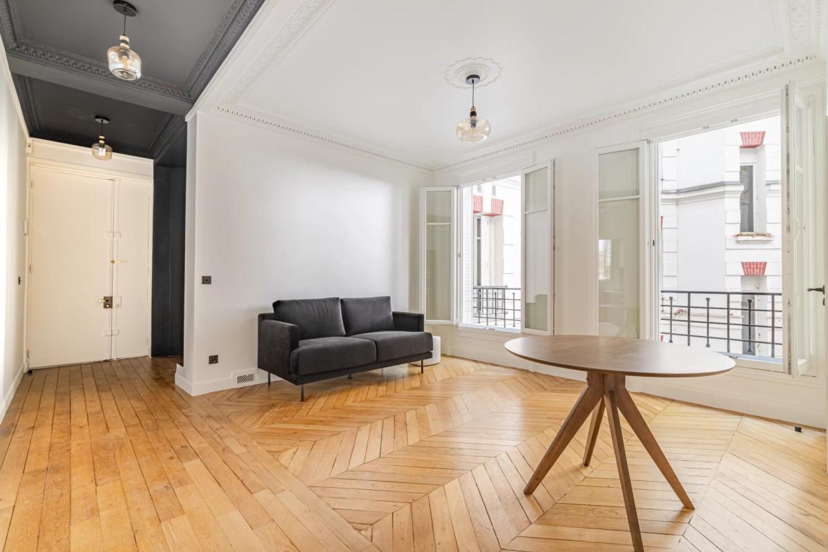 Interior of a renovated 75m² apartment with a living room and windows overlooking a tree-lined courtyard.
