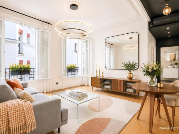 Bright living room of a renovated apartment with grey sofa, glass table and modern decor.