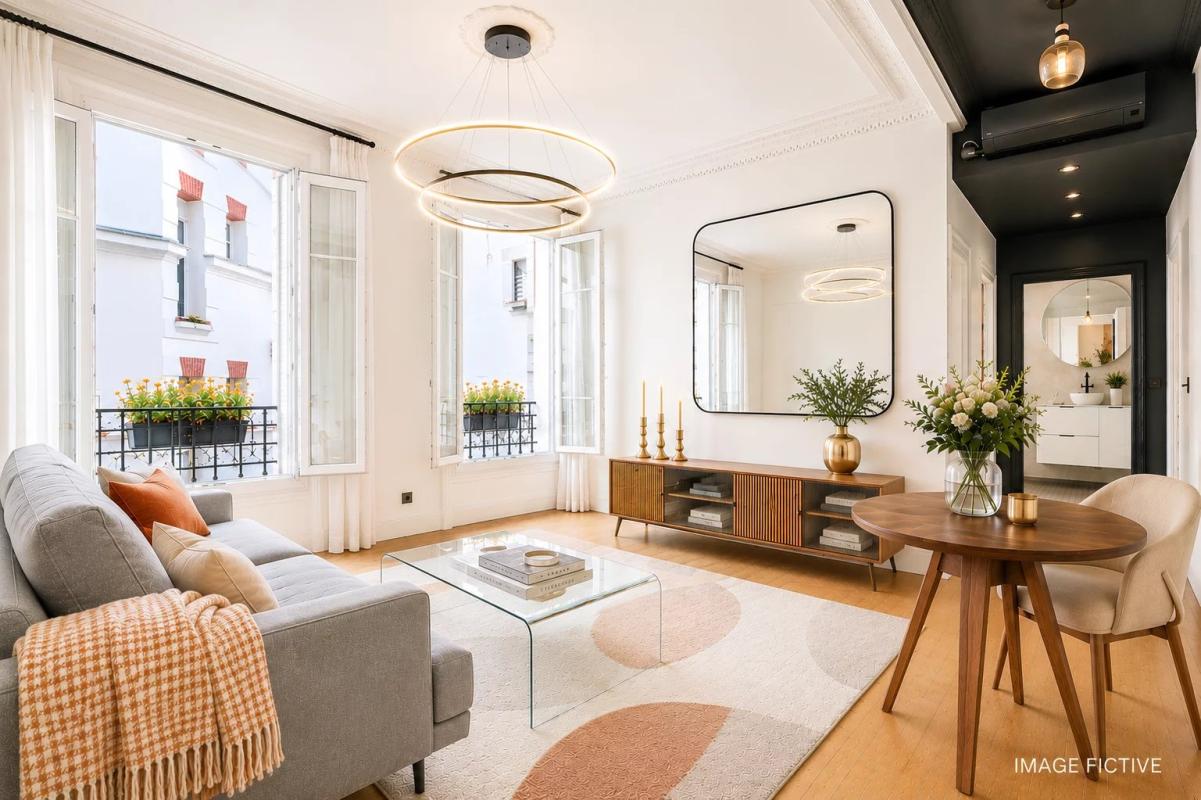 Bright living room of a renovated apartment with grey sofa, glass table and modern decor.