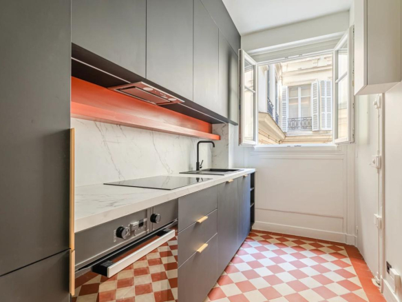Modern kitchen with windows overlooking a tree-lined courtyard in a renovated apartment in Paris 7th arrondissement.