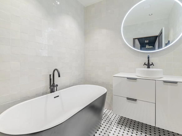 Modern bathroom with bathtub and sink, black and white tiles.