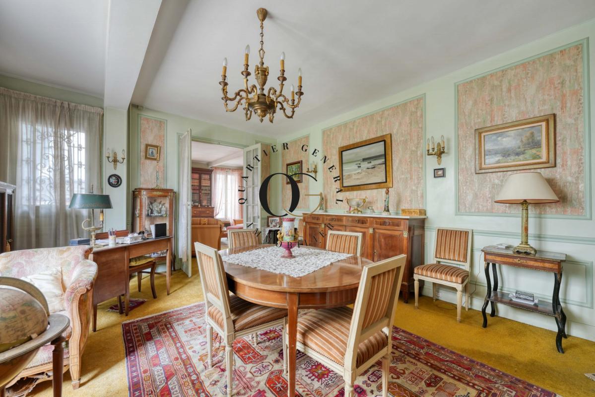 Intérieur d’une maison bourgeoise à Saint-Ouen-sur-Seine Intérieur d'une maison bourgeoise avec salle à manger, mobilier ancien et tapis, à Saint-Ouen-sur-Seine.