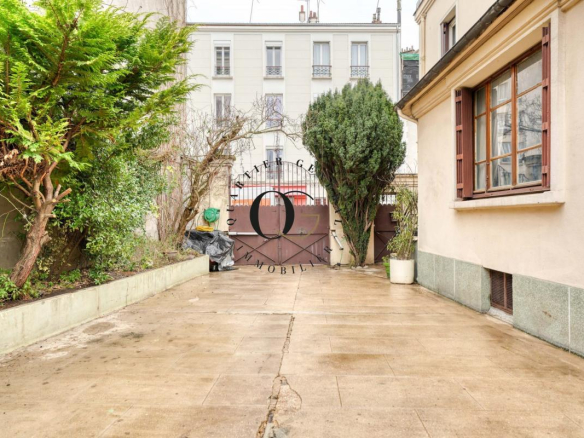 Entrée d'une maison bourgeoise avec cour à Saint-Ouen-sur-Seine, murs végétalisés et portail en fer.
