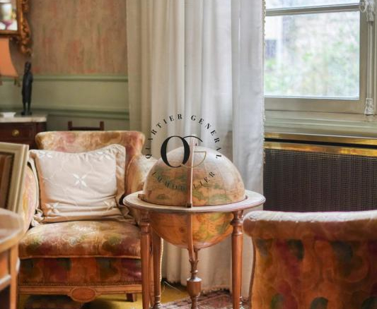 Intérieur d'une maison bourgeoise avec un globe terrestre et des canapés anciens.