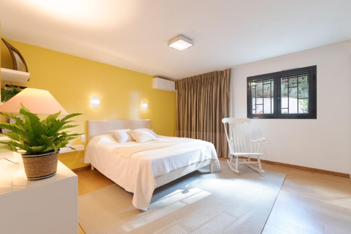 Room in a villa in Biot Bright room with yellow walls and double bed, rocking chair and windows.