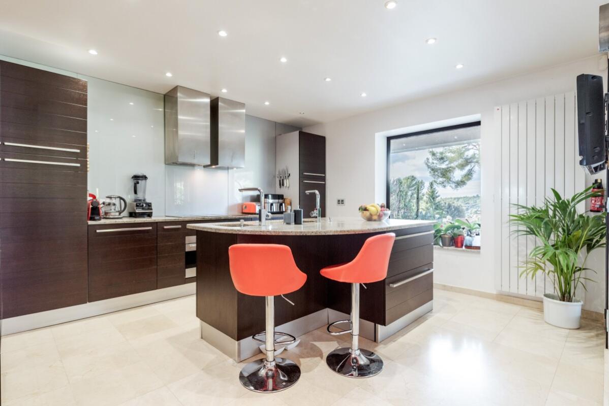 Modern kitchen in a villa in Biot Modern kitchen with central island and bar, potted plants in the window.