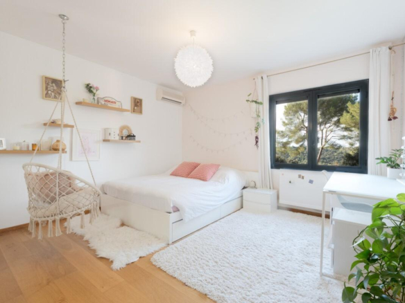 Bright bedroom with bed, desk and minimalist decor.
