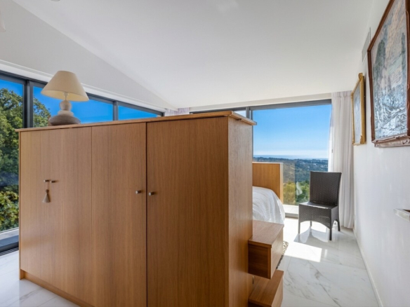 Chambre avec vue panoramique sur la mer et les montagnes à Gattières, mobilier en bois clair.