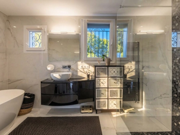 Salle de bain moderne avec baignoire, lavabo et douche, décorée de carrelage en marbre.