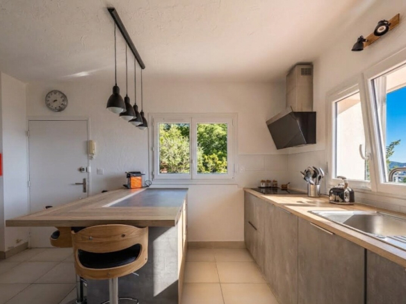 Cuisine moderne et lumineuse avec un îlot central, vue sur la mer à Gattières.
