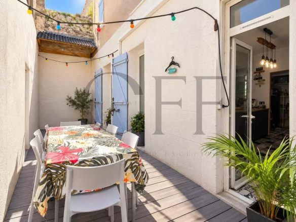 Courtyard terrace of a townhouse in Marseille, with a table and chairs, decorated with string lights.