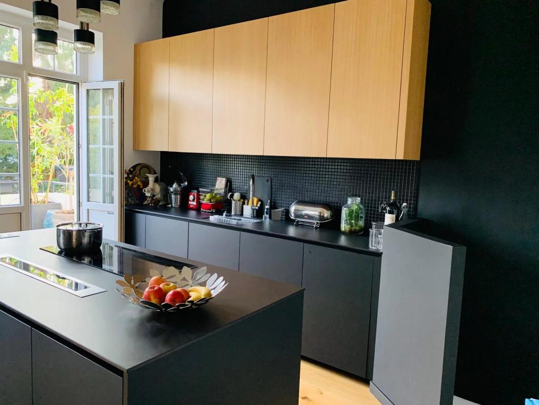 Cuisine moderne dans un duplex à Strasbourg Cuisine moderne avec îlot central et placards en bois, ouverte sur un jardin.