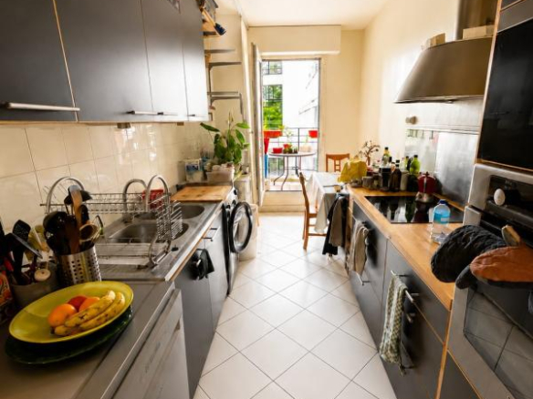 Cuisine d'un appartement avec des meubles modernes et un accès à une terrasse.