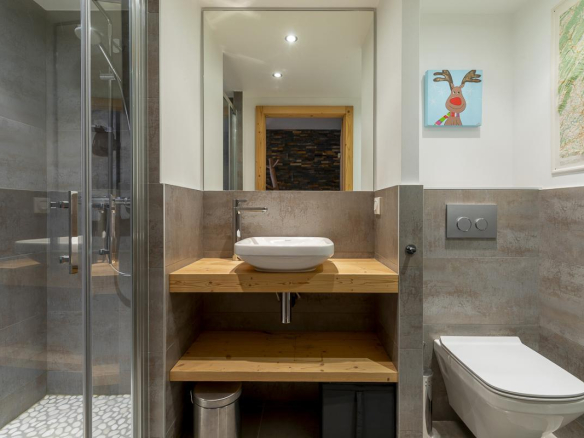 Salle de bain moderne avec douche, lavabo sur meuble en bois et toilettes.