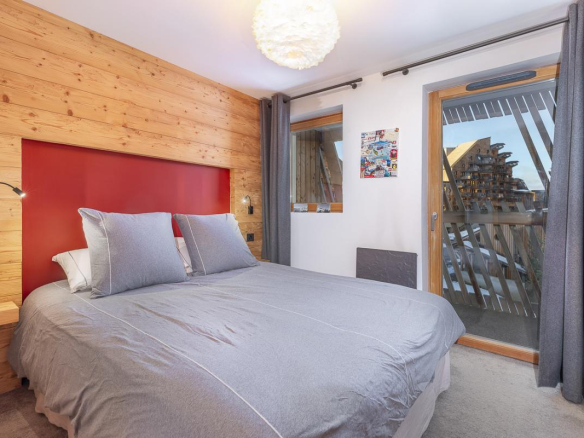 Chambre d'un duplex avec lit double et balcon, décor en bois à Avoriaz.