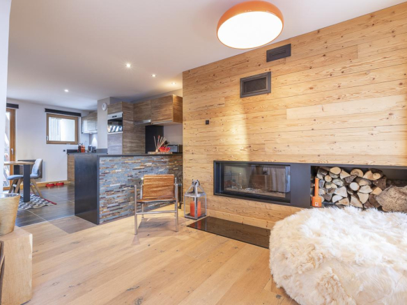 Intérieur d'un duplex élégant avec cheminée et cuisine ouverte, résidence du Kouria à Avoriaz.