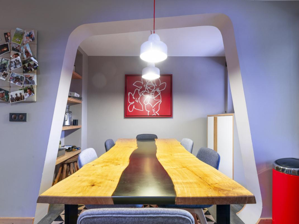 Salle à manger d'un duplex moderne avec une grande table en bois et des chaises, décorée de photos au mur.