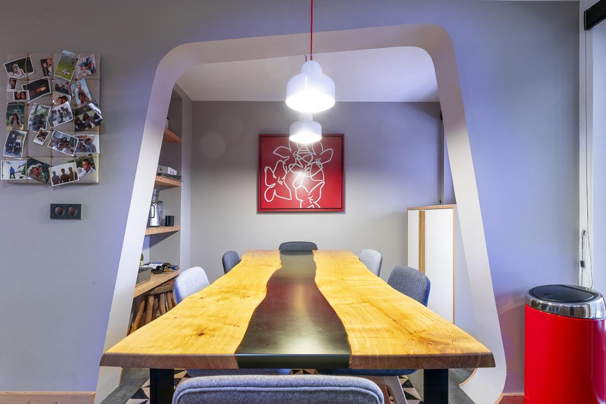 Salle à manger du duplex au Kouria Salle à manger d'un duplex moderne avec une grande table en bois et des chaises, décorée de photos au mur.
