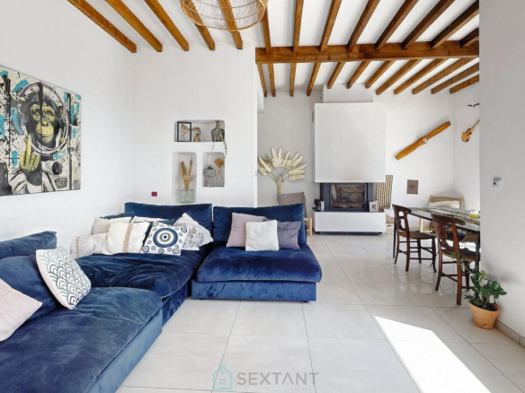 Intérieur d'une villa moderne avec un grand canapé bleu et des poutres apparentes.
