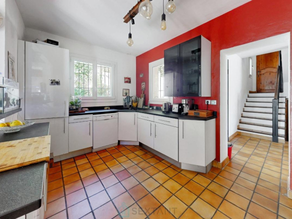 Cuisine moderne dans une villa à Istres avec carrelage en terre cuite et murs rouges.