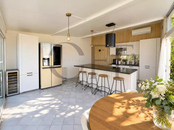 Cuisine moderne avec îlot central et bar, éclairage naturel, vue sur la mer.