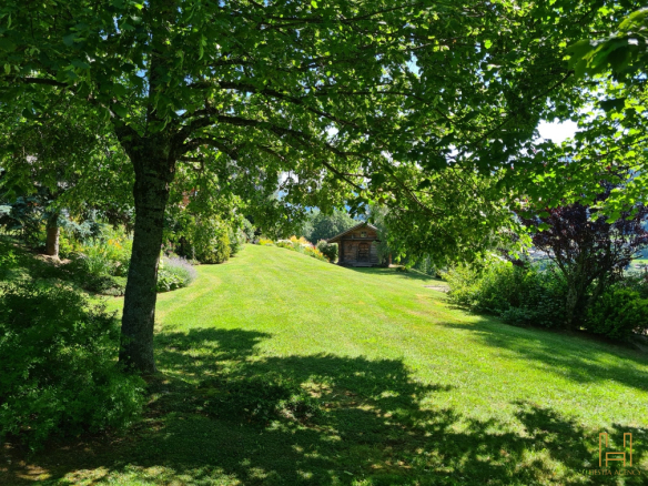 Landscaped garden with wooden chalet, surrounded by trees in Demi-Quartier.