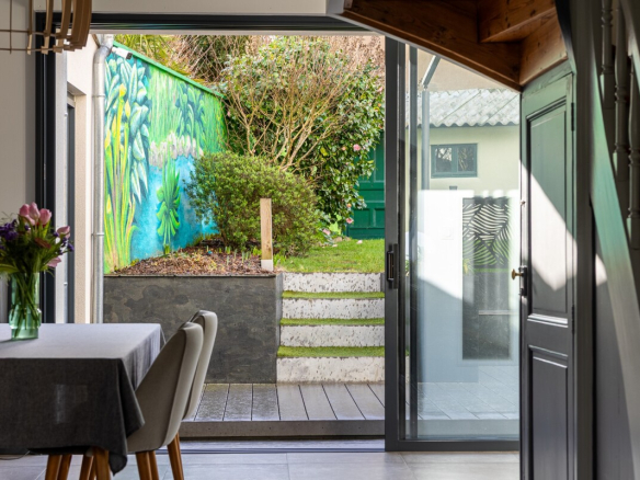 Interior of a house in Nantes with a view of a garden and a colorful mural.