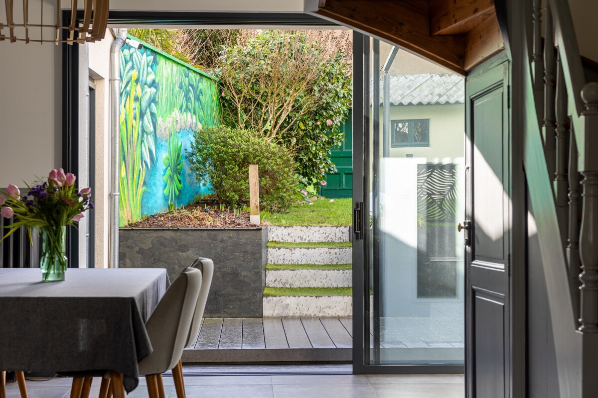 Interior of a house in Nantes with a view of a garden and a colorful mural.