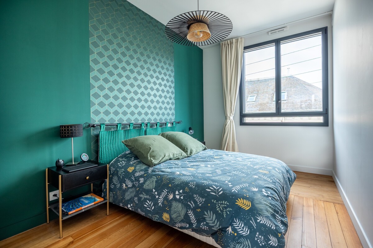 Bedroom in a house in Nantes with green walls and a bed decorated with cushions.