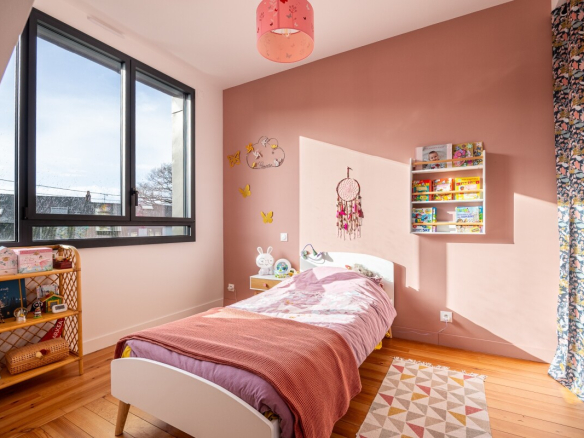 Children's bedroom with single bed, pink walls and large window in Nantes.