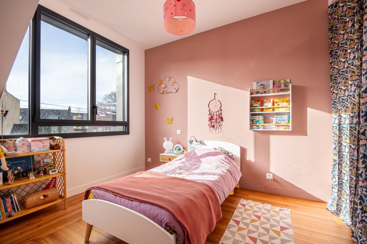 Children's bedroom with single bed, pink walls and large window in Nantes.