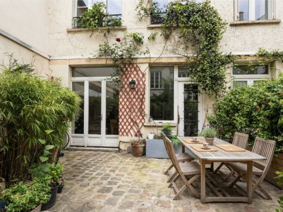 Terrasse d'une maison atypique avec des plantes et une table en bois à Paris.