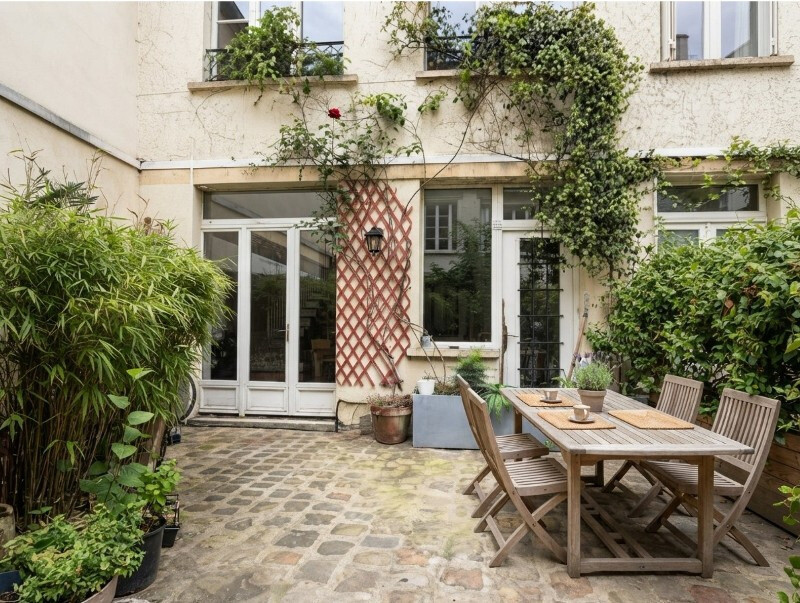 Terrasse d’une maison atypique à Paris Terrasse d'une maison atypique avec des plantes et une table en bois à Paris.