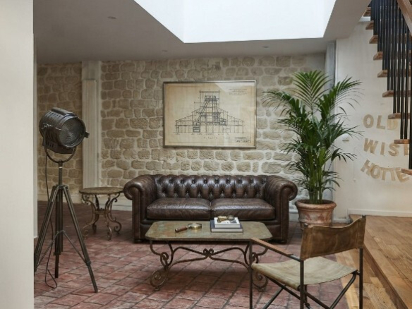 Intérieur d'une maison atypique avec canapé en cuir, plante, et décor en pierre apparente.