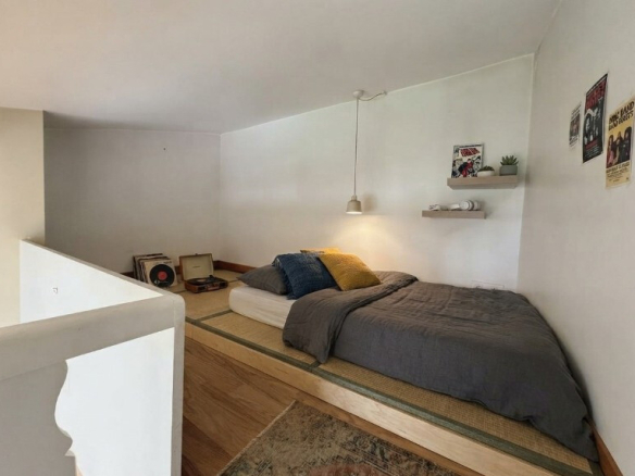 Chambre avec lit surélevé et décoration minimaliste dans une maison à Paris.