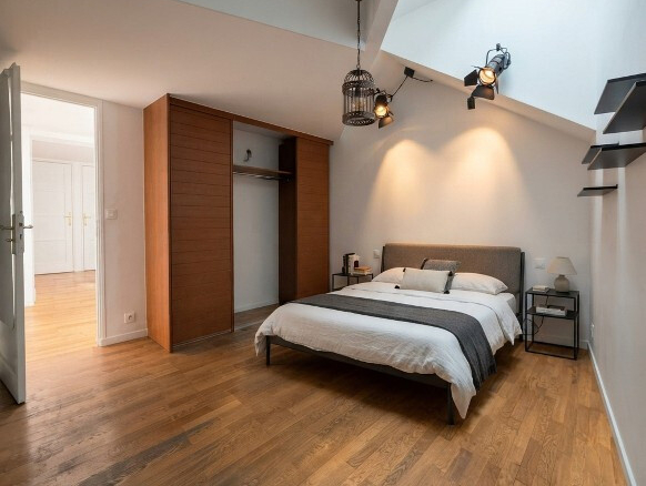 Chambre d'une maison atypique à Paris 19ème, avec lit, parquet en bois et lumière naturelle.