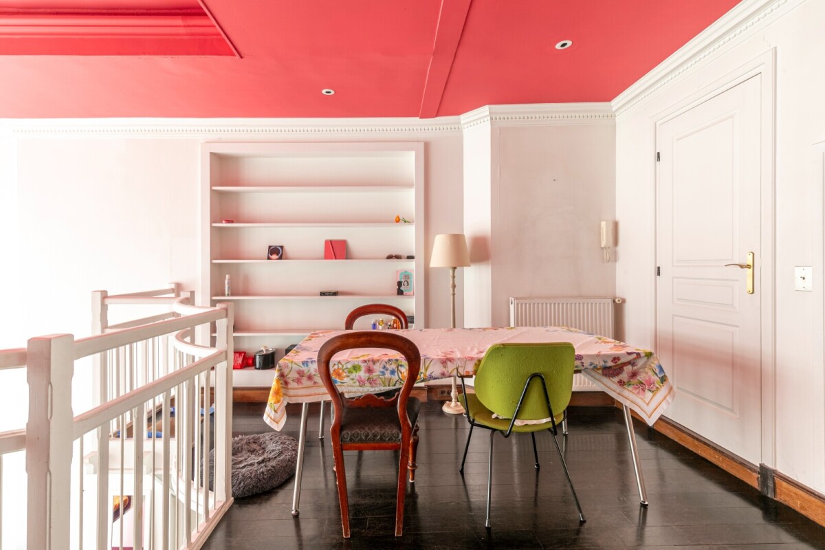 Atelier d’artiste à Paris Intérieur d'un atelier d'artiste avec une table et des chaises, murs clairs et plafond rouge.