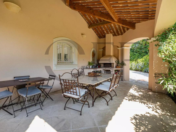 Terrasse couverte avec table et chaises, entourée de verdure dans une villa à Marseille 12ᵉ.