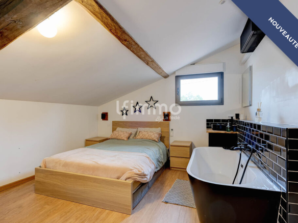 Room in a renovated property with bathtub, bed and modern decor.