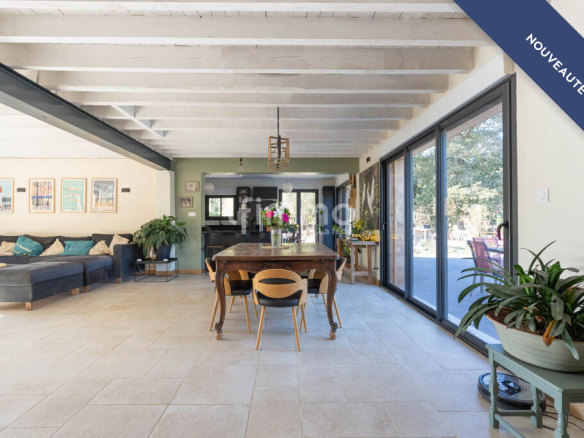 Interior of a renovated house with a large dining table and a bright living room.